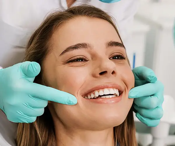 Primo piano di donna che sorride mostrando denti sani e naturali, all'aperto.